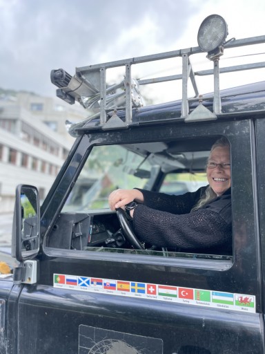 kvinne i landrover med mange flagg
